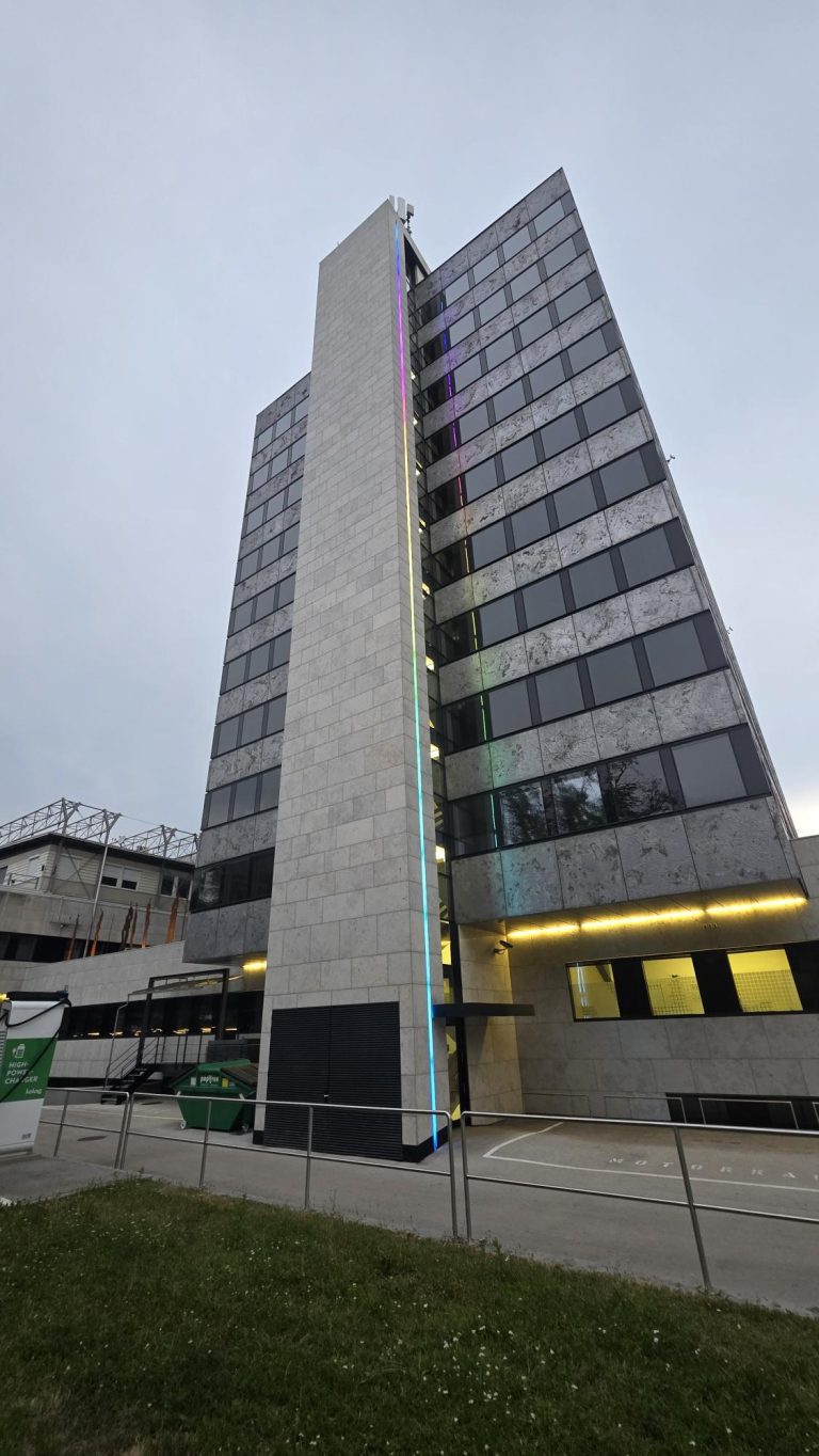 Bürohochhaus in Klagenfurt in der Abenddämmerung mit farbigen RGBW-Lichtlinien an der Fassade