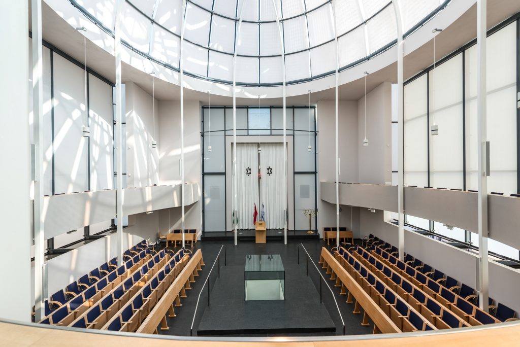 Innenraum der Synagoge Graz mit Glaskuppel, hellen Wänden und Sitzreihen