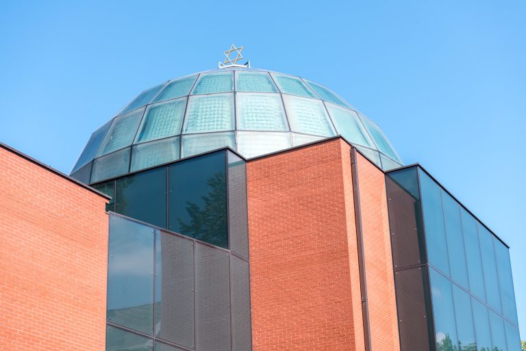 Außenansicht der Synagoge Graz mit Glaskuppel über Ziegelbau vor blauem Himmel
