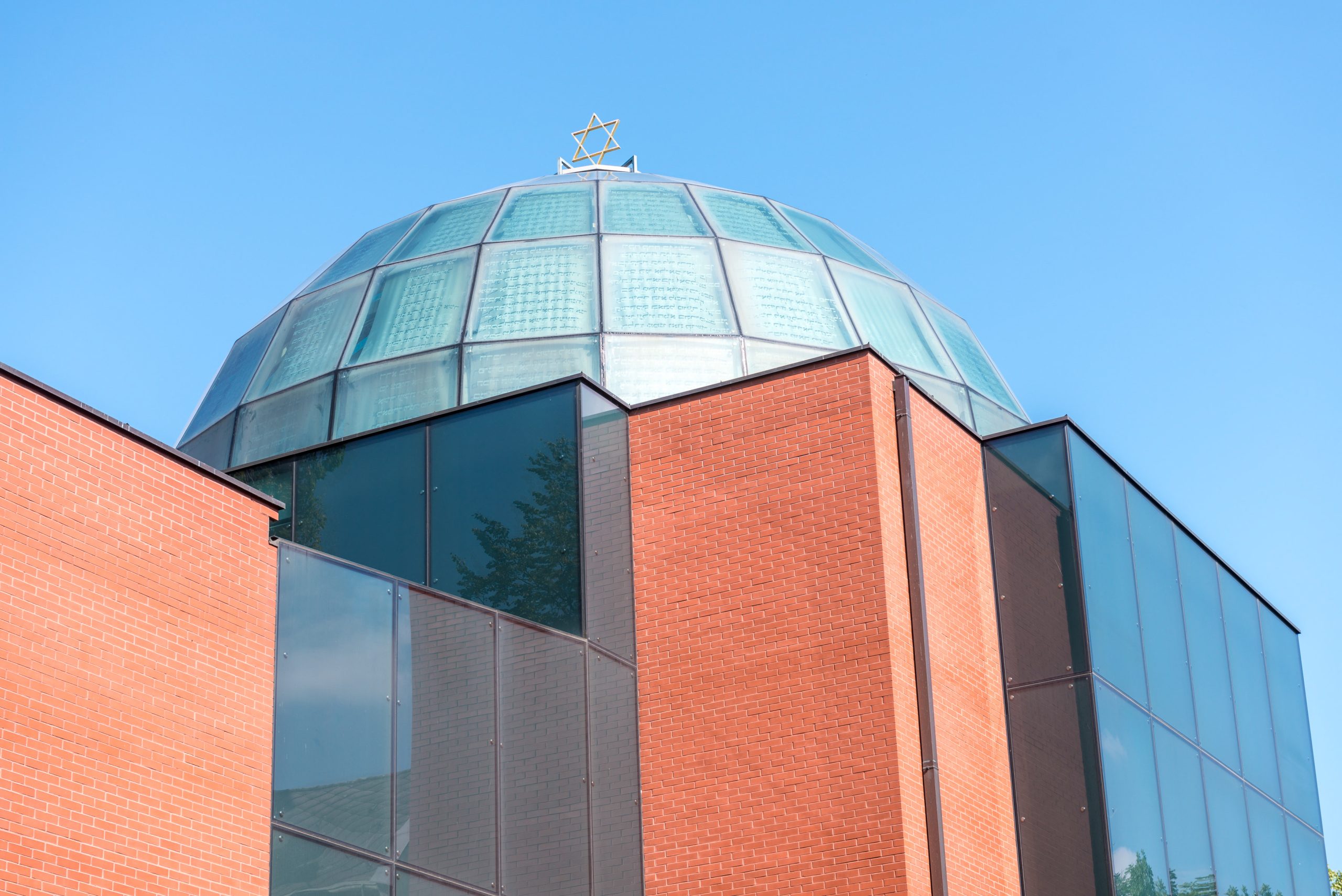 Außenansicht der Synagoge Graz mit Glaskuppel über Ziegelbau vor blauem Himmel